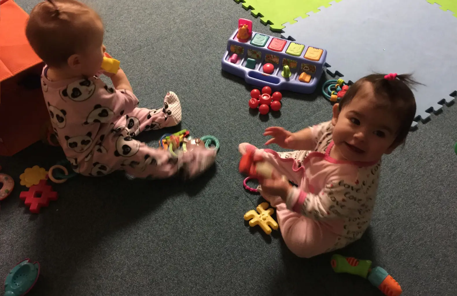 Babies playing with toys on carpet.