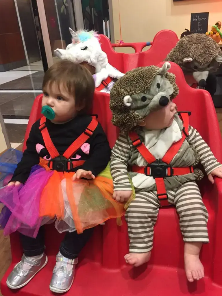 Two toddlers in costumes sitting together.