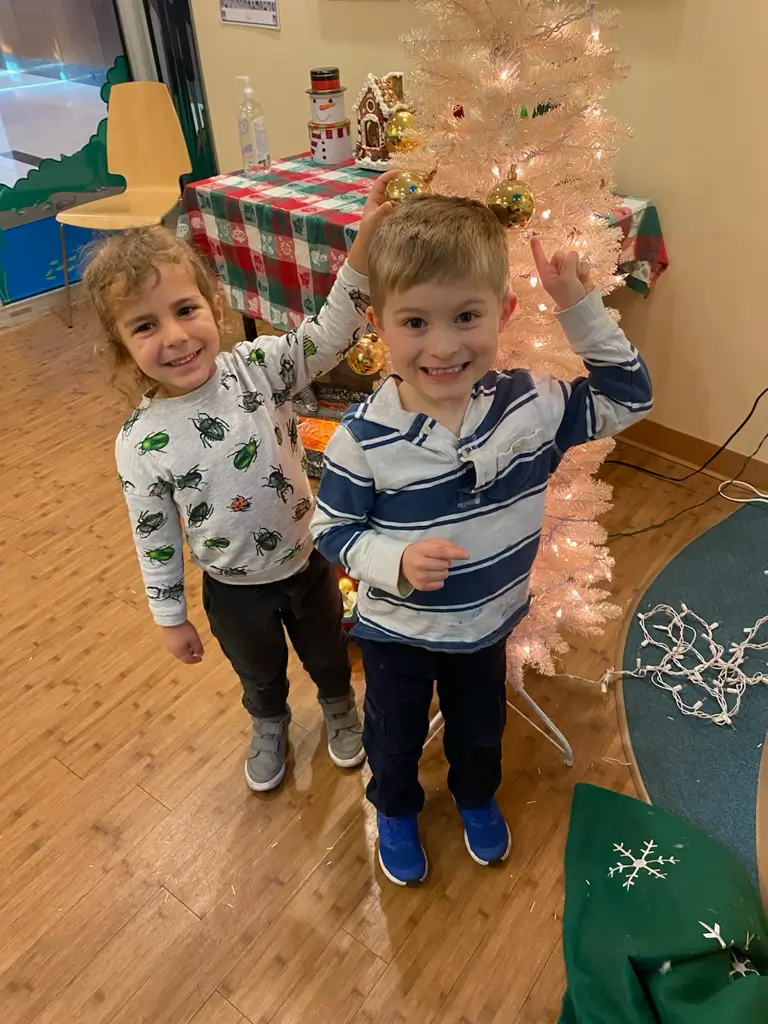 Children decorating a Christmas tree indoors.