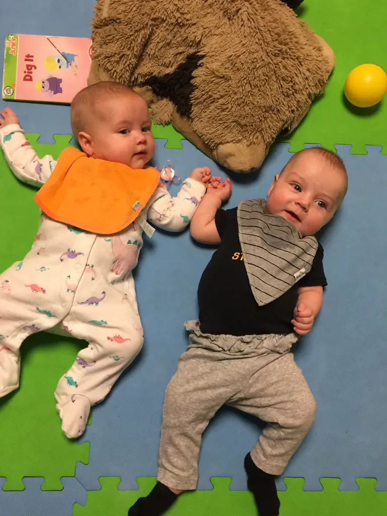 Babies lying on colorful play mat.