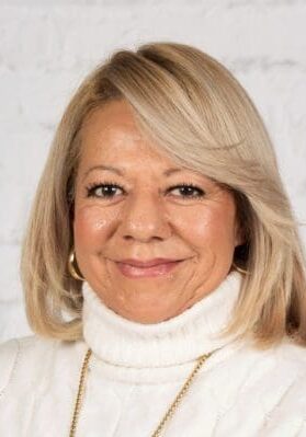 Smiling woman with blonde hair in a white turtleneck sweater.